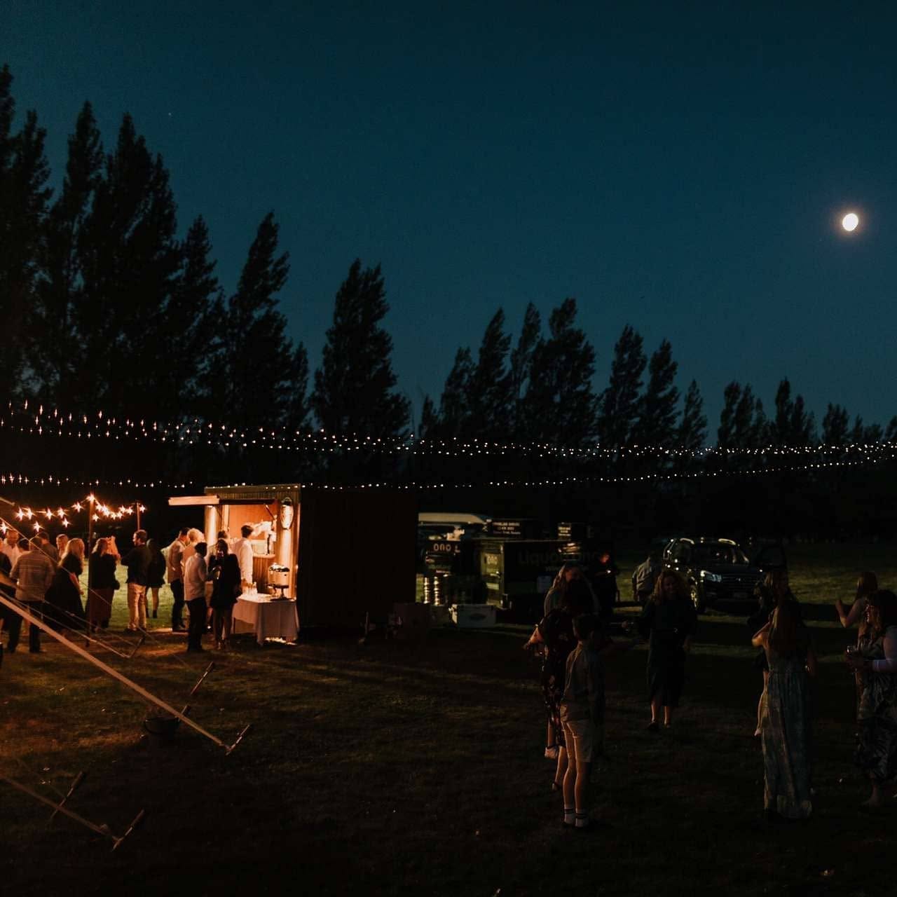 The Tow Bar lit up at a night event under string lights